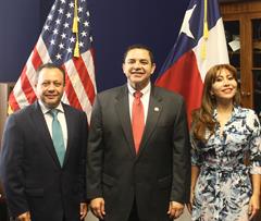 Congressman Henry Cuellar stands and smiles between Mexican Congressman Braulio Guerra and Mexican Congresswoman Liliana Oropeza, in front of the flags of the United States and Texas. 